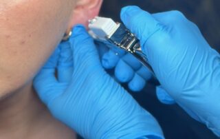 Client receiving a Sterex 9ct gold ear piercing at SKIN lounge Aesthetics Richmond, using a sterile, professional technique for safe results.