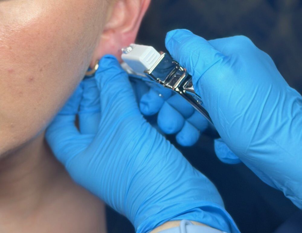 Client receiving a Sterex 9ct gold ear piercing at SKIN lounge Aesthetics Richmond, using a sterile, professional technique for safe results.